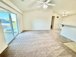 Cypress Upstairs Vaulted Living Room with Fan and Carpeted Floors, Glass Sliding Patio Door to Balcony at Hawthorne Properties in Lafayette, IN 47905