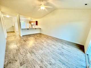 the living room and kitchen of an empty home with a ceiling fan at Hawthorne Properties in Lafayette, IN 47905
