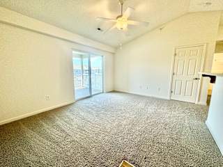 an empty living room with a ceiling fan and a door to a balcony at Hawthorne Properties in Lafayette, IN 47905