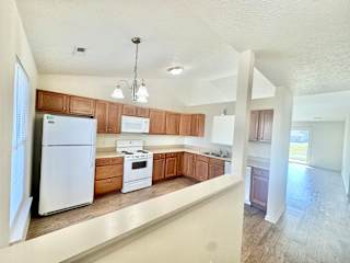 an empty kitchen with white appliances and wooden cabinets at Hawthorne Properties in Lafayette, IN 47905