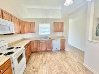 an empty kitchen with wooden cabinets and white appliances at Hawthorne Properties in Lafayette, IN 47905