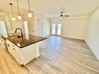 A spacious kitchen with a sink, cabinets, and a ceiling fan.