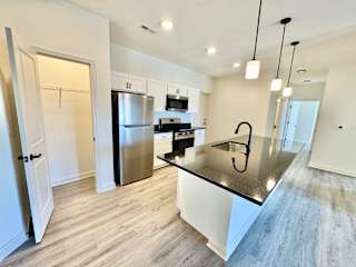 A modern kitchen with a stainless steel refrigerator and a black countertop.