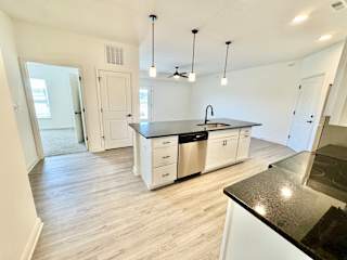 A kitchen with a black counter top and white cabinets.