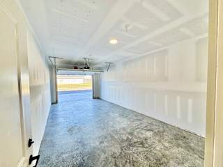 A long, empty hallway with a concrete floor and white walls.