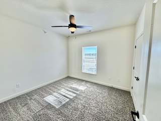 A room with a ceiling fan and a poster on the wall.