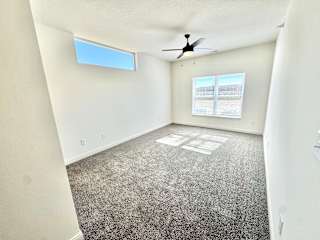 A room with a ceiling fan and a window with blinds.