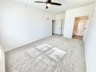 A room with a ceiling fan and a carpeted floor.