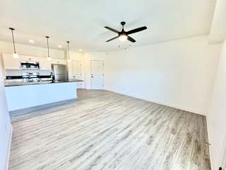 A spacious kitchen with a ceiling fan and lighting fixtures.