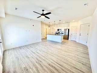 A spacious room with a ceiling fan and a kitchen island in the middle.