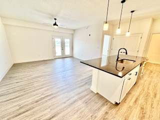 A kitchen with white cabinets and a black countertop.