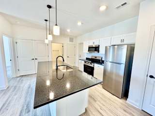 A modern kitchen with a granite countertop and stainless steel appliances.