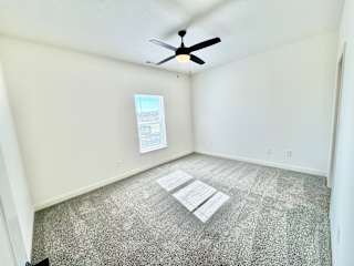 A room with a ceiling fan and a window with blinds.