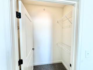 A white closet with a door open and a shelf on the wall.