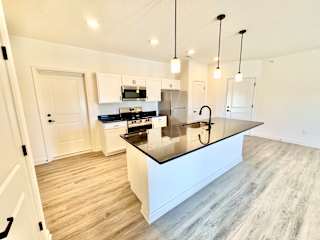 A modern kitchen with a large island and pendant lights.
