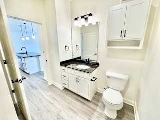 A white bathroom with a toilet, sink, and mirror.