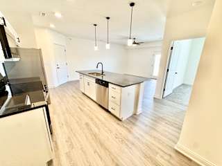 A kitchen with a black fridge and a black counter top.