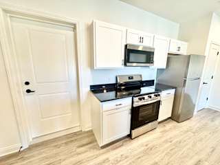 A kitchen with white cabinets and a black countertop.