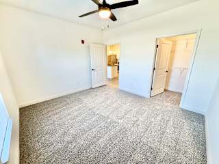A room with a ceiling fan and carpeted floor.