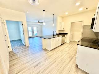 A kitchen with white cabinets and a black countertop.