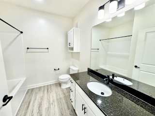 A bathroom with a toilet, sink, and mirror.