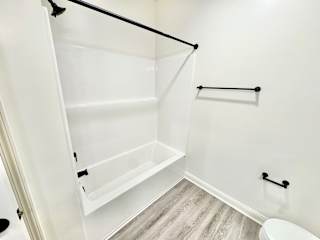 A white bathroom with a toilet and a walk-in shower.