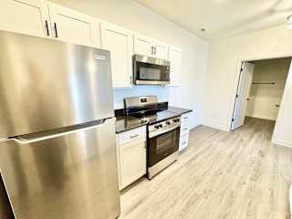 A kitchen with a stainless steel refrigerator and a black stove top oven.