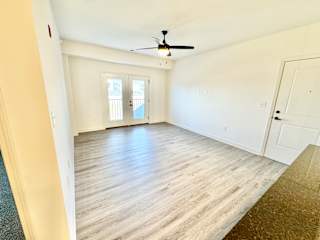 A room with a ceiling fan and a door leading to a balcony.