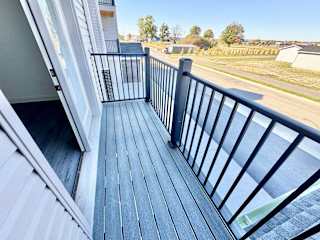 A balcony with a black railing and wooden floor.