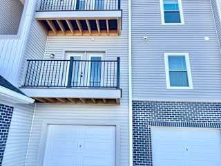A balcony with a black railing and a window with a white frame.