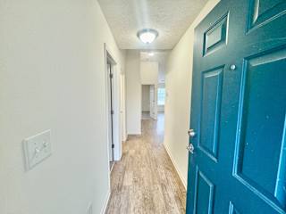 a hallway with a blue door and white walls and wood floors at Hawthorne Properties in Lafayette, IN 47905