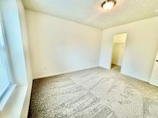 an empty living room with carpet and a door to a closet at Hawthorne Properties in Lafayette, IN 47905