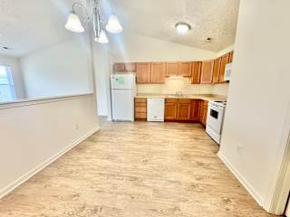 an empty kitchen with white appliances and wooden cabinets at Hawthorne Properties in Lafayette, IN 47905
