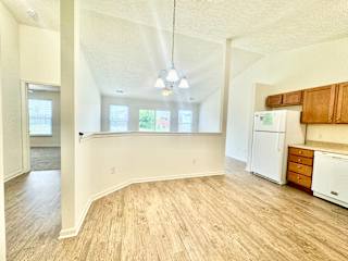 an empty kitchen and living room with white appliances and wood floors at Hawthorne Properties in Lafayette, IN 47905