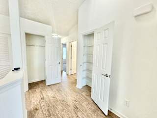 an empty room with white doors and a hallway with white closets at Hawthorne Properties in Lafayette, IN 47905