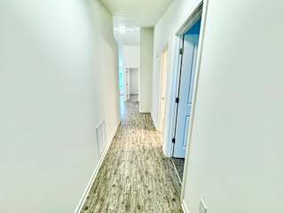 an empty hallway with white walls and a wood floor at Hawthorne Properties in Lafayette, IN 47905