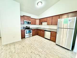 an empty kitchen with wooden cabinets and stainless steel appliances at Hawthorne Properties in Lafayette, IN 47905
