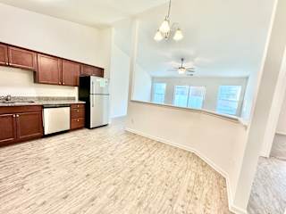 an empty kitchen and living room with wood flooring and white walls at Hawthorne Properties in Lafayette, IN 47905