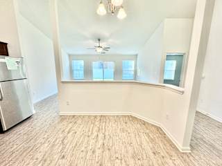 an empty living room with a large window and a kitchen at Hawthorne Properties in Lafayette, IN 47905
