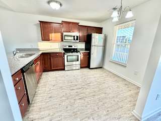 an empty kitchen with wooden cabinets and stainless steel appliances at Hawthorne Properties in Lafayette, IN 47905