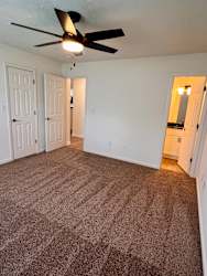 A room with a ceiling fan and carpeted floor.