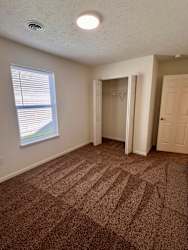 A room with a carpeted floor and a window with blinds.