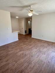 A room with a ceiling fan and light fixture, and a wooden floor.
