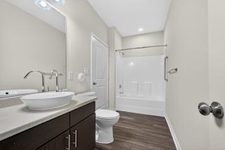 A white toilet sits in a bathroom with a white sink and a white shower.