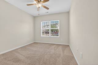 A room with a ceiling fan and a carpeted floor.