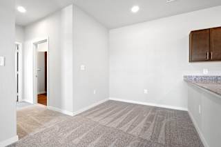 an empty living room with white walls and carpet and a kitchen  at Aventura at Hawk Ridge, Lake St Louis, MO, 63367