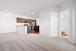 an empty living room with a kitchen with a stove and a refrigerator  at Aventura at Hawk Ridge, Missouri, 63367