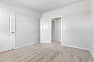 a bedroom with white walls and carpet and a door to a closet  at Aventura at Hawk Ridge, Lake St Louis
