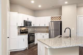 A kitchen with white cabinets and a granite countertop.