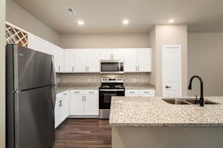 A kitchen with a refrigerator, oven, and sink.